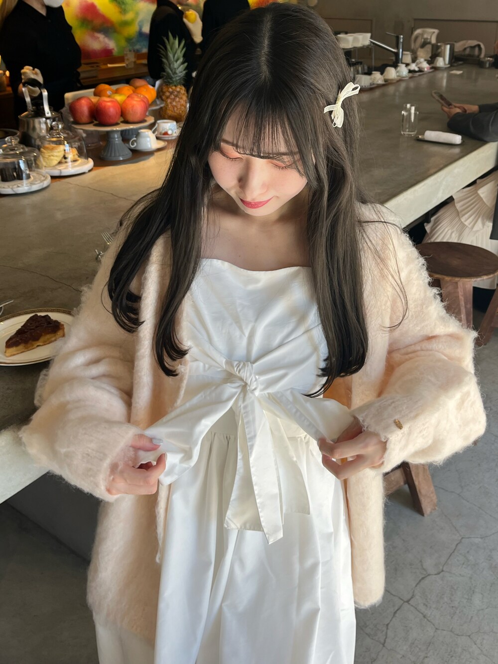 ピンク系のカーディガン/ボレロ、ホワイト系のワンピース/ドレス、ブラック系のシューズを着用したレディースの春コーディネートの2枚目の写真