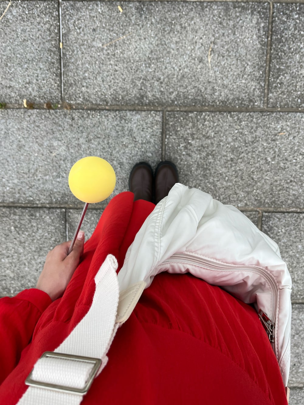 ホワイト系のショルダーバッグ、レッド系のワンピース、ブラウン系のブーツを着用したレディースの夏コーディネートの4枚目の写真