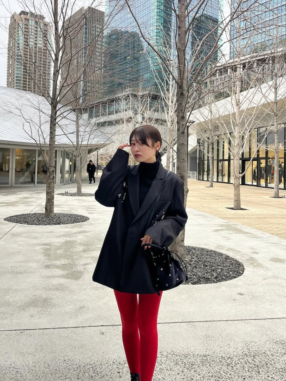ブラック系のテーラードジャケット、ブラック系のハンドバッグ、ブラック系のブーツを着用したレディースの春コーディネートの5枚目の写真