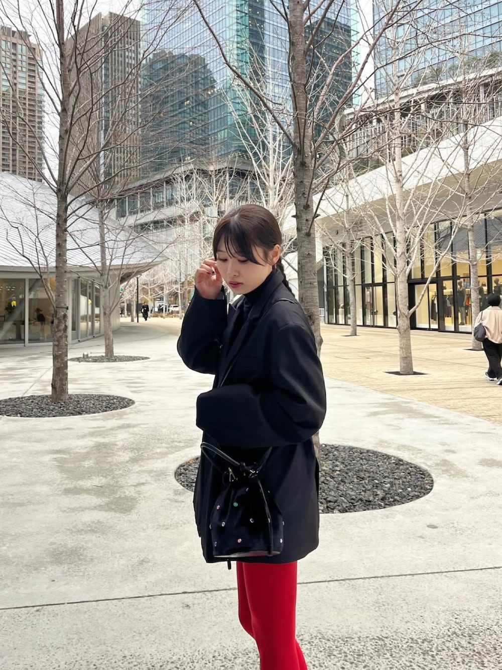 ブラック系のテーラードジャケット、ブラック系のハンドバッグ、ブラック系のブーツを着用したレディースの春コーディネートの2枚目の写真