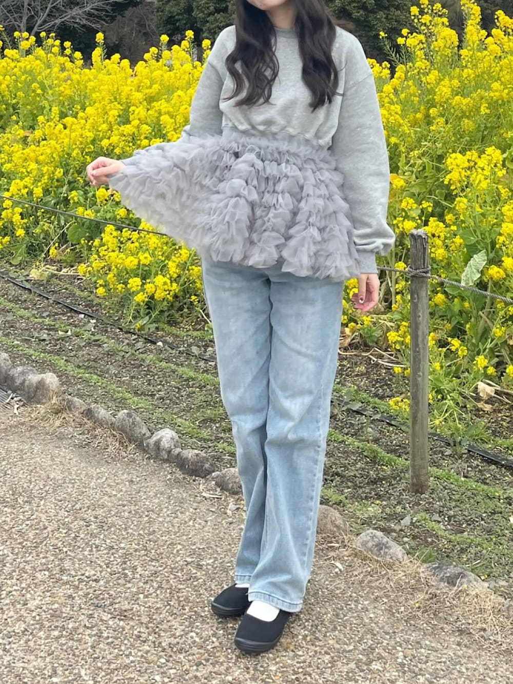 グレー系のスウェット、ブルー系のデニムパンツ、ブラック系のバレエシューズを着用したレディースの春コーディネートの2枚目の写真