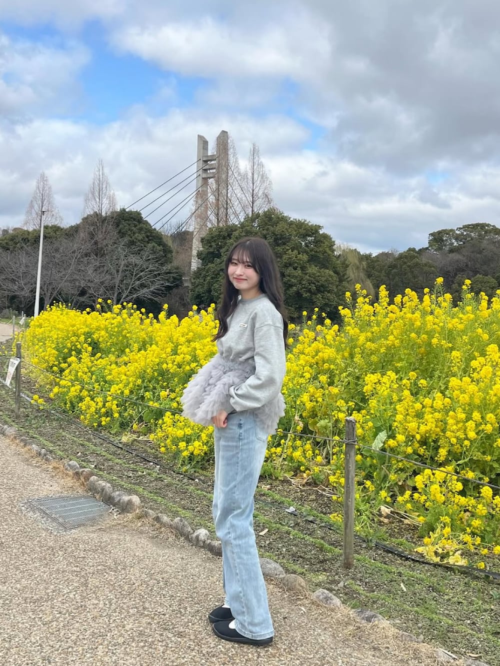 グレー系のスウェット、ブルー系のデニムパンツ、ブラック系のバレエシューズを着用したレディースの春コーディネートの3枚目の写真