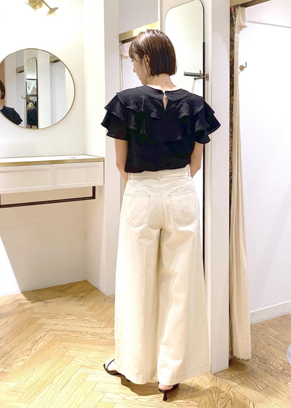 ホワイト系のショルダーバッグ、ブラック系のシャツ/ブラウス、ホワイト系のデニムパンツを着用したレディースの夏コーディネートの3枚目の写真