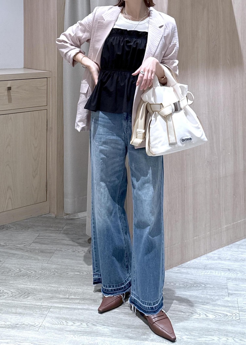 ホワイト系のトートバッグ、ブルー系のデニムパンツ、ブラック系のニット/セーターを着用したレディースの春コーディネートの7枚目の写真