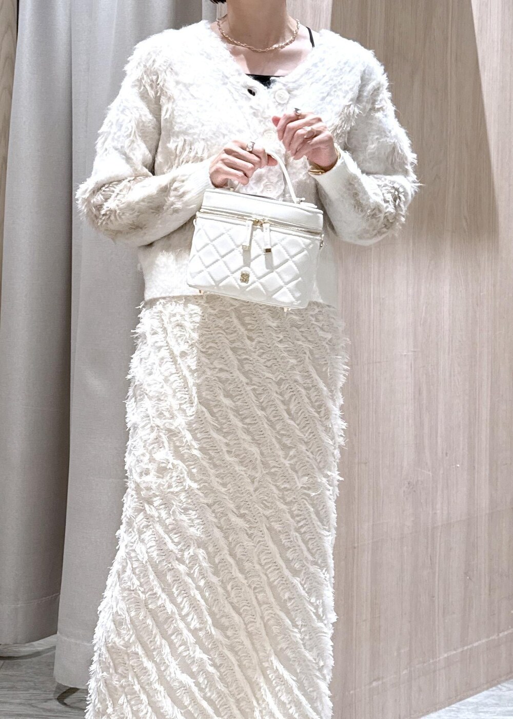 ホワイト系のスカート、ベージュ系のブーツ、ホワイト系のハンドバッグを着用したレディースの秋コーディネートの6枚目の写真