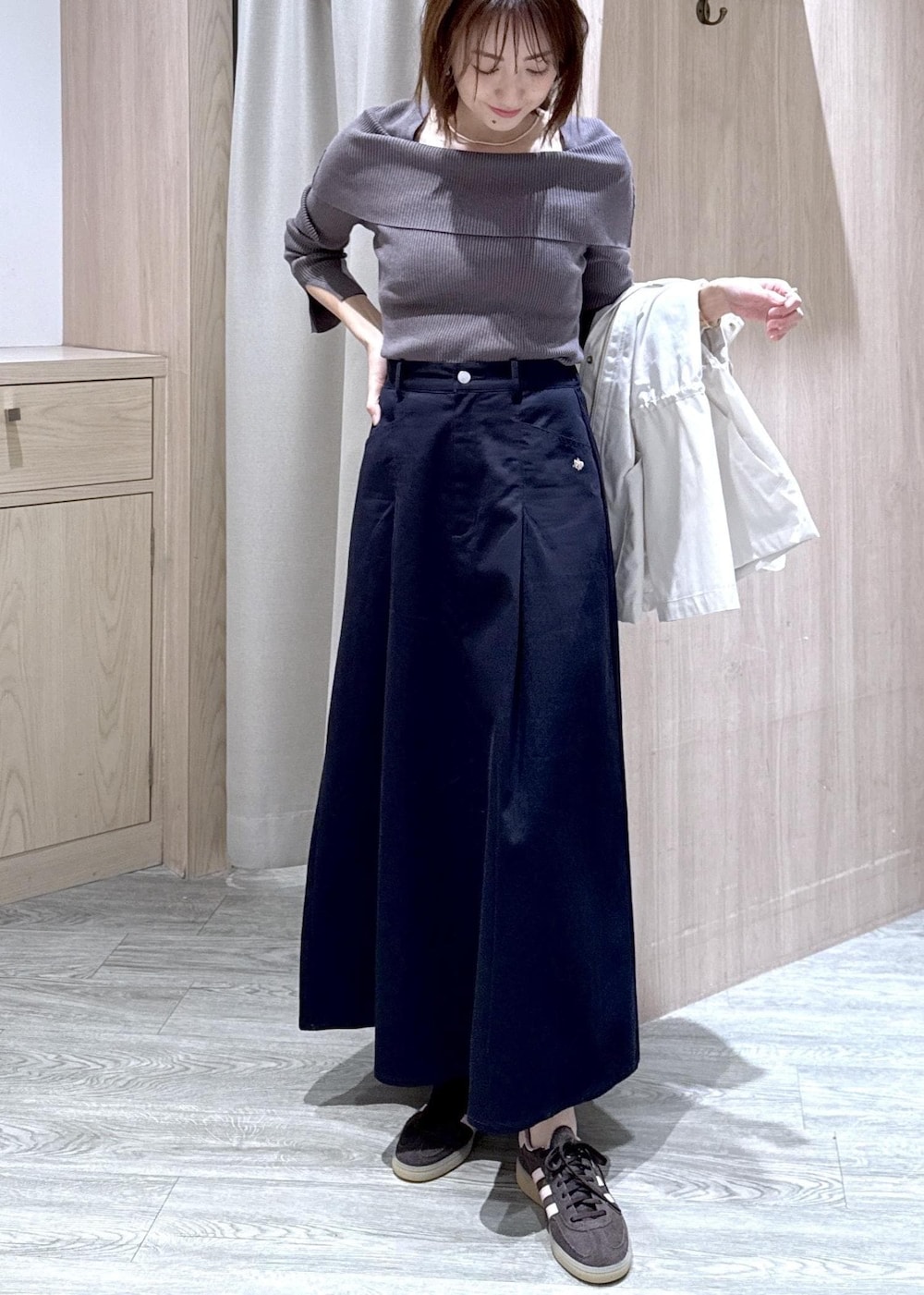 グレー系のニット/セーター、ブルー系のスカート、ホワイト系のナイロンジャケットを着用したレディースの春コーディネートの7枚目の写真