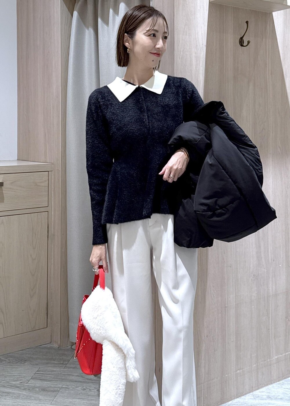 ブラック系のダウンジャケット/コート、ホワイト系のスラックス、ブラック系のニット/セーターを着用したレディースの冬コーディネートの5枚目の写真