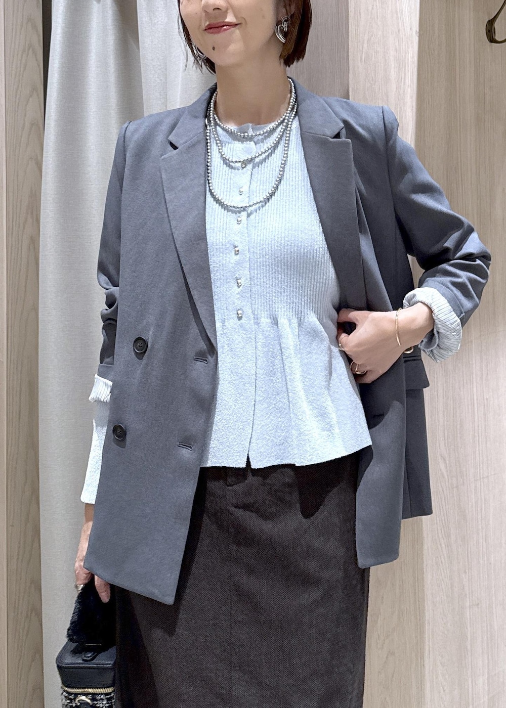 グレー系のテーラードジャケット、ブルー系のカーディガン/ボレロ、ブラウン系のスカートを着用したレディースの秋コーディネートの7枚目の写真