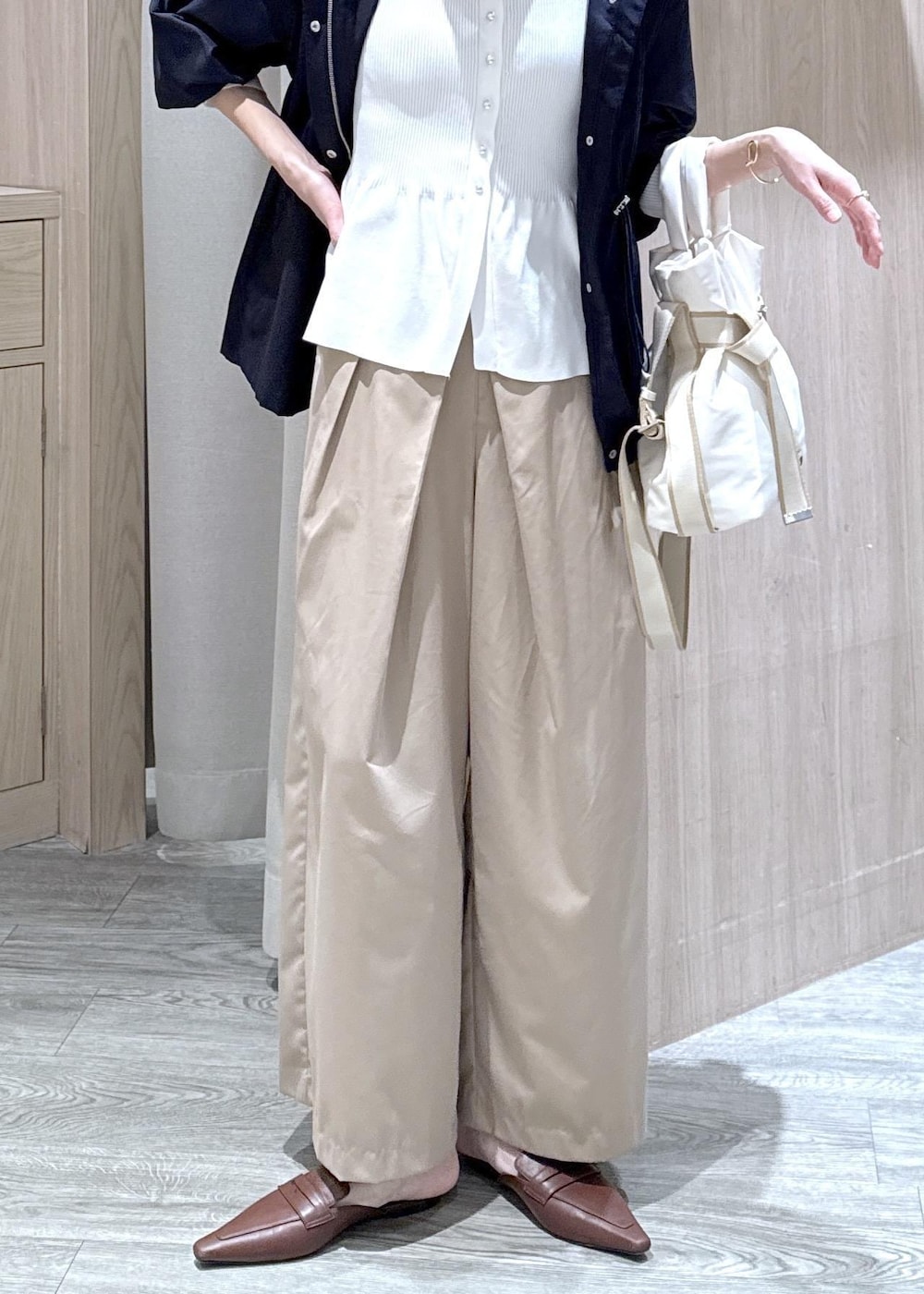 ホワイト系のカーディガン/ボレロ、ホワイト系のトートバッグ、ブルー系のナイロンジャケットを着用したレディースの春コーディネートの4枚目の写真