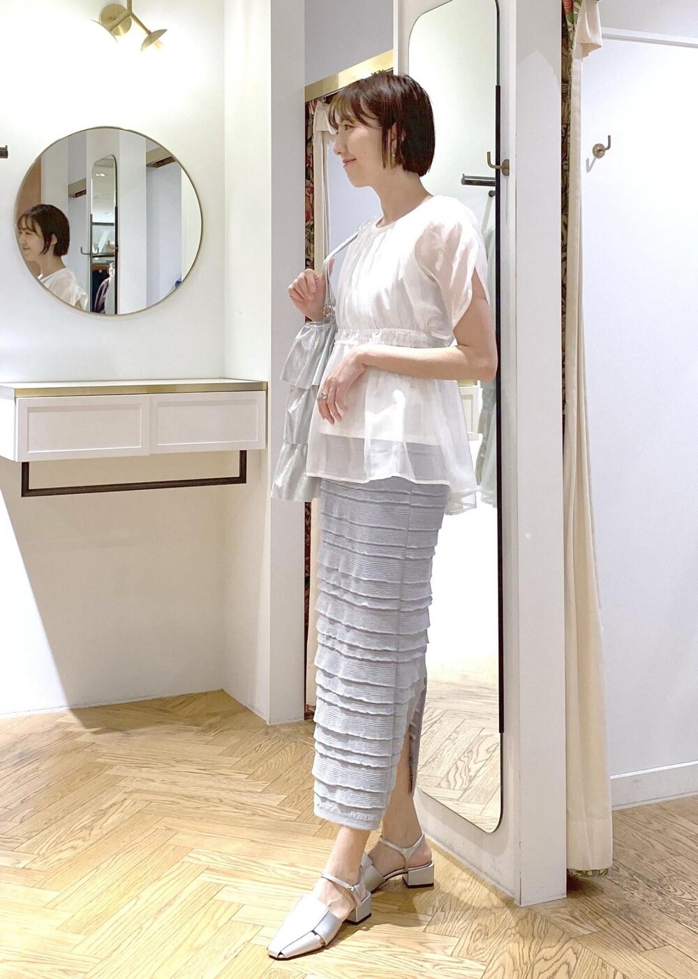 シルバー系のサンダル、シルバー系のトートバッグ、ホワイト系のTシャツ/カットソーを着用したレディースの夏コーディネートの2枚目の写真