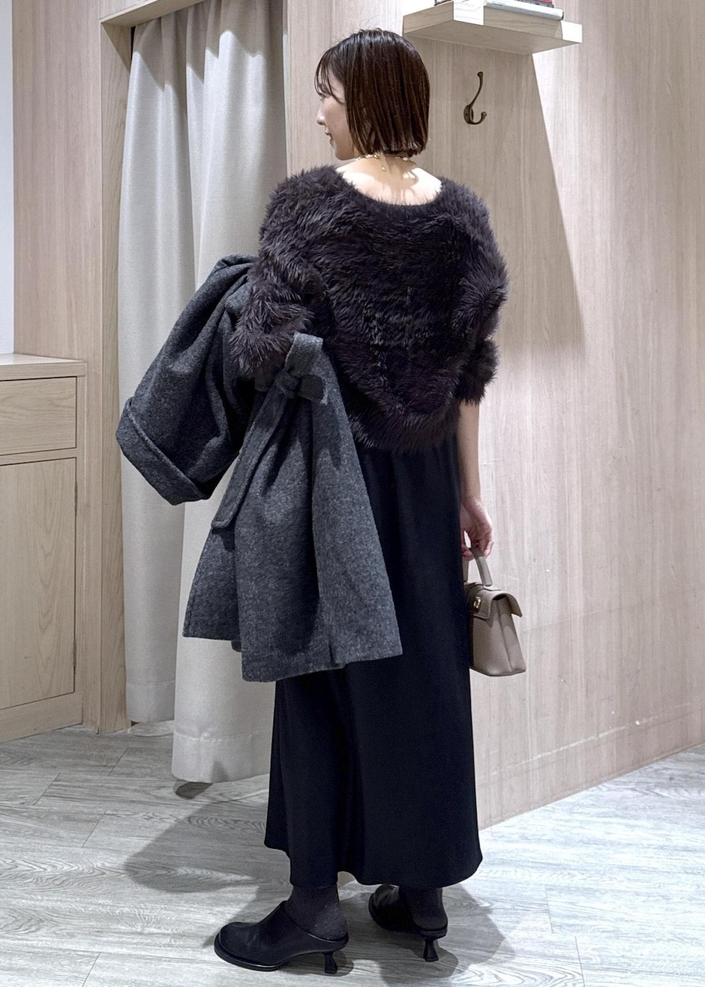 ベージュ系のショルダーバッグ、グレー系のその他アウター、ブラック系のスカートを着用したレディースの冬コーディネートの2枚目の写真