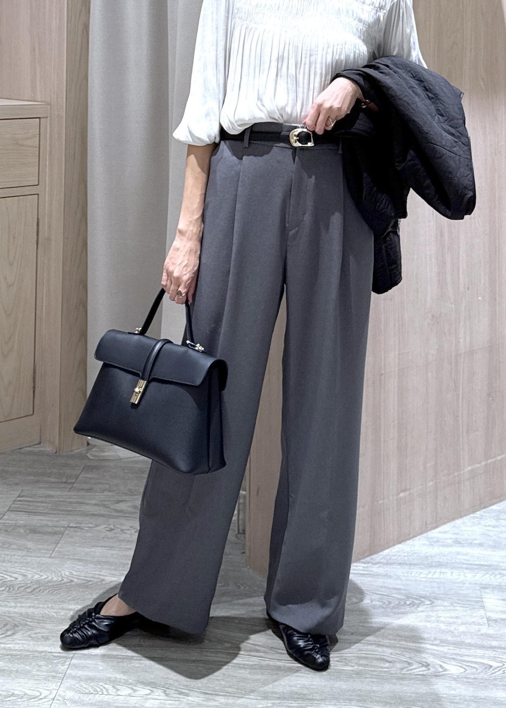 ブラック系のハンドバッグ、グレー系のスラックス、ホワイト系のシャツ/ブラウスを着用したレディースの秋コーディネートの3枚目の写真