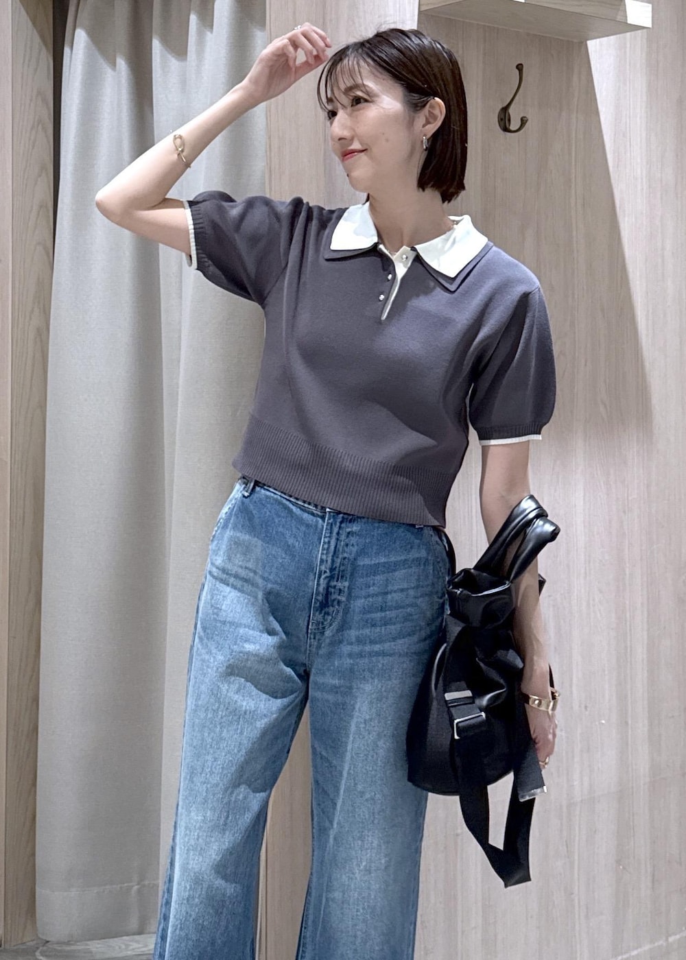 ホワイト系のキャミソール、ブラック系のトートバッグ、ブルー系のデニムパンツを着用したレディースの春コーディネートの5枚目の写真