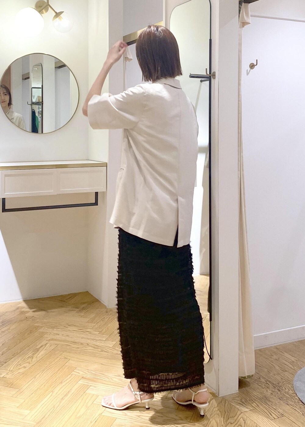 ブラック系のハンドバッグ、ホワイト系のサンダル、ホワイト系のシャツ/ブラウスを着用したレディースの春コーディネートの2枚目の写真