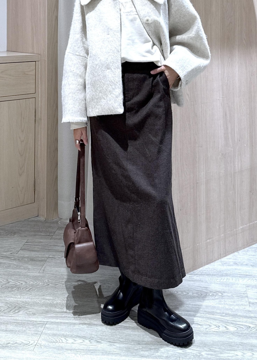 ブラウン系のショルダーバッグ、ブラック系のブーツ、ホワイト系のブルゾンを着用したレディースの秋コーディネートの2枚目の写真