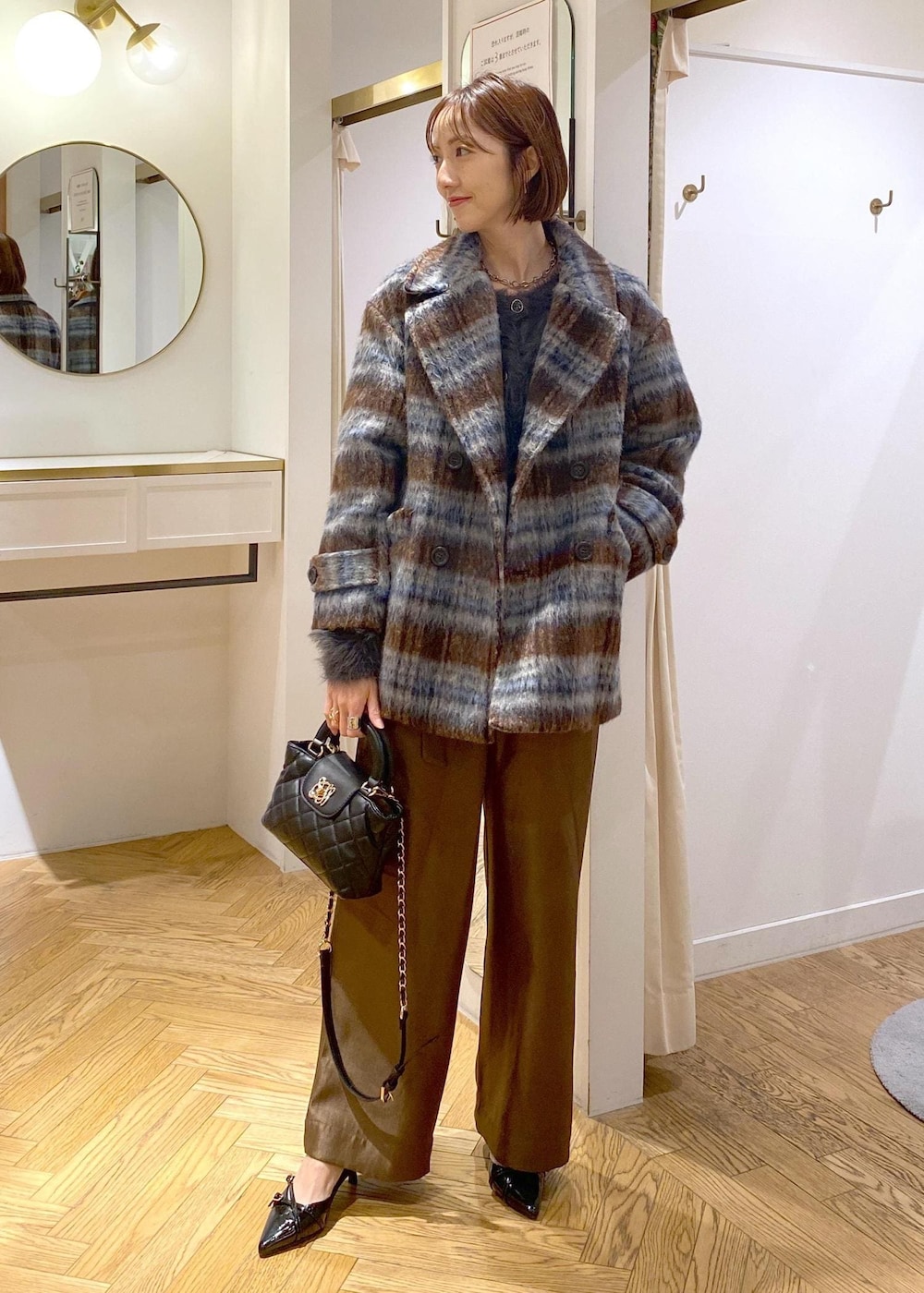 ブラック系のパンプス、グレー系のカーディガン/ボレロ、ブラウン系のピーコートを着用したレディースの冬コーディネートの2枚目の写真