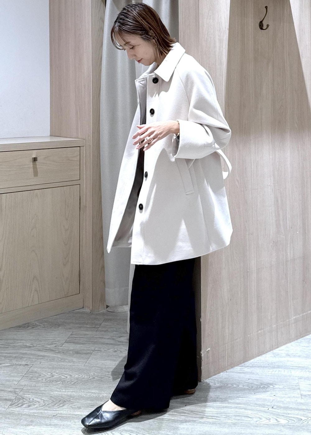 ブラック系のスラックス、ブラック系のショルダーバッグ、ブルー系のニット/セーターを着用したレディースの秋コーディネートの4枚目の写真