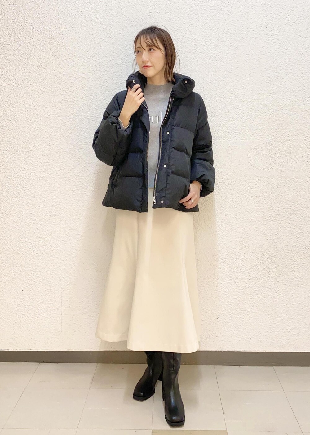 ブラック系のダウンジャケット/コート、ブラック系のブーツ、グレー系のニット/セーターを着用したレディースの冬コーディネートの2枚目の写真
