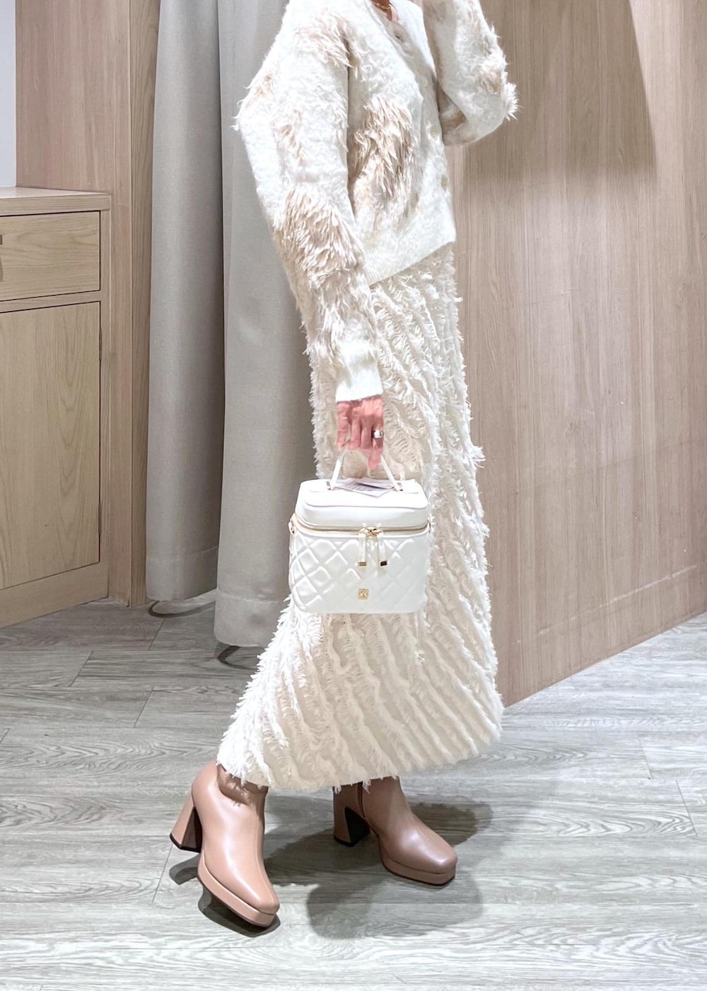 ホワイト系のスカート、ベージュ系のブーツ、ホワイト系のハンドバッグを着用したレディースの秋コーディネートの9枚目の写真