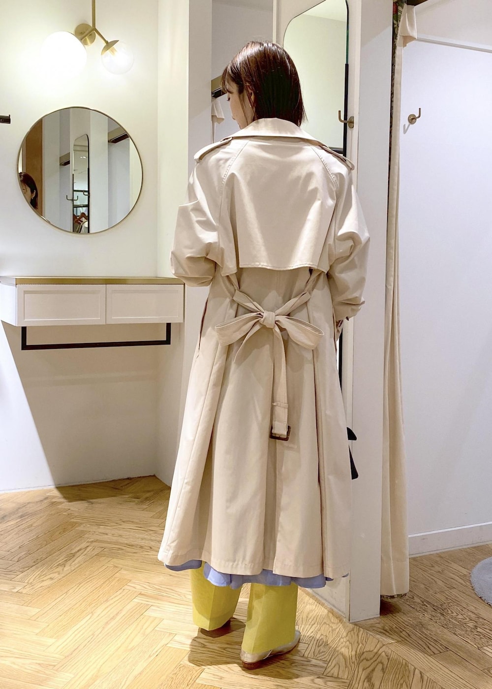 シルバー系のパンプス、ブルー系のシャツワンピース、ホワイト系のトレンチコートを着用したレディースの春コーディネートの2枚目の写真