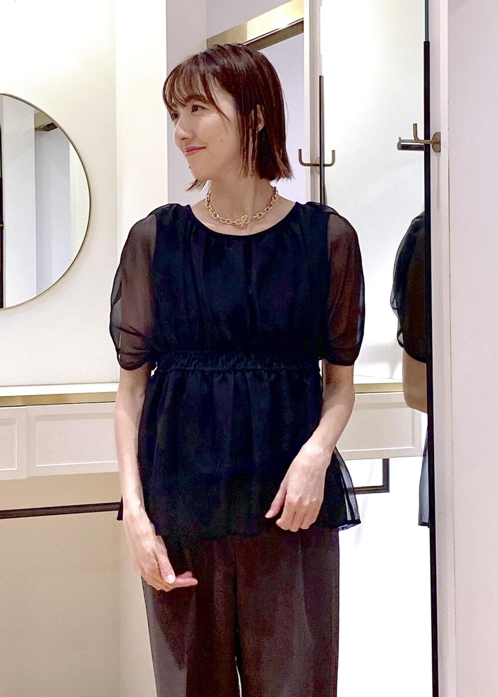 ブラック系のサンダル、ブラック系のハンドバッグ、グレー系のスラックスを着用したレディースの夏コーディネートの4枚目の写真