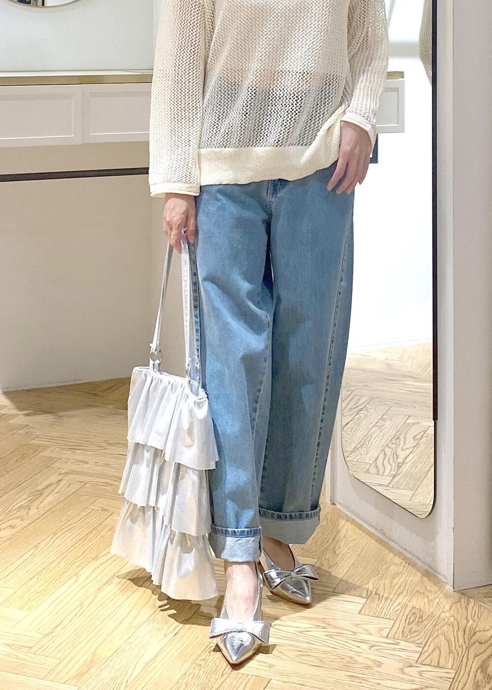 シルバー系のパンプス、シルバー系のトートバッグ、ブルー系のデニムパンツを着用したレディースの夏コーディネートの7枚目の写真