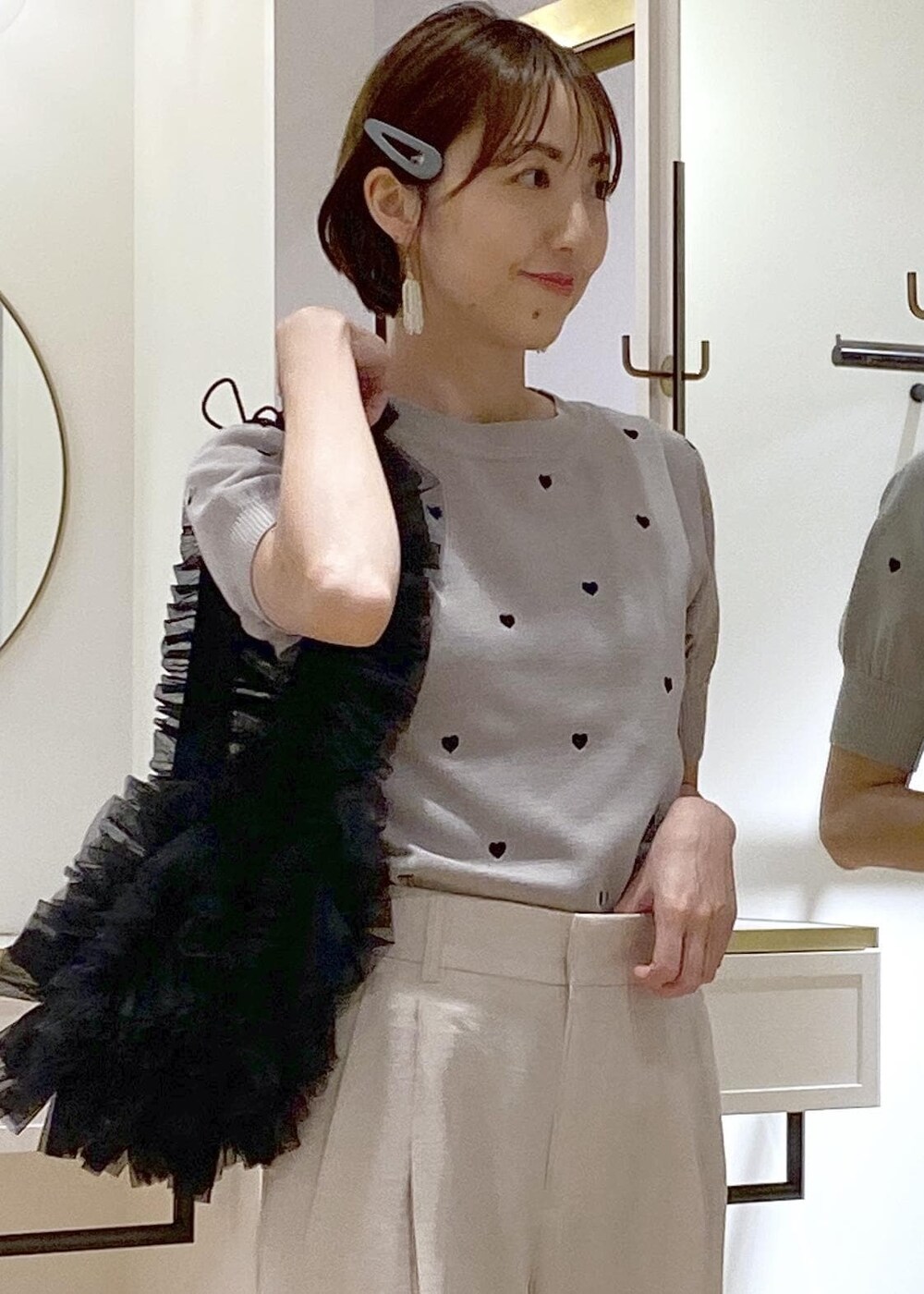 ブラック系のショルダーバッグ、グレー系のニット/セーター、ホワイト系のスラックスを着用したレディースの夏コーディネートの4枚目の写真