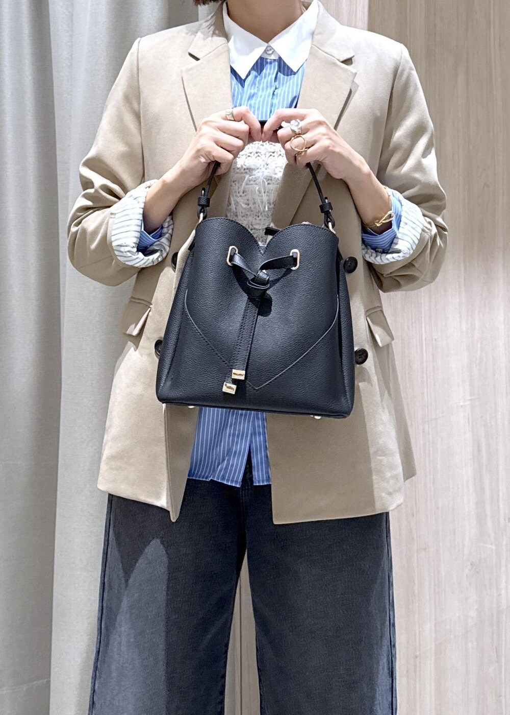 ブラック系のショルダーバッグ、ベージュ系のテーラードジャケット、ブラック系のブーツを着用したレディースの秋コーディネートの6枚目の写真