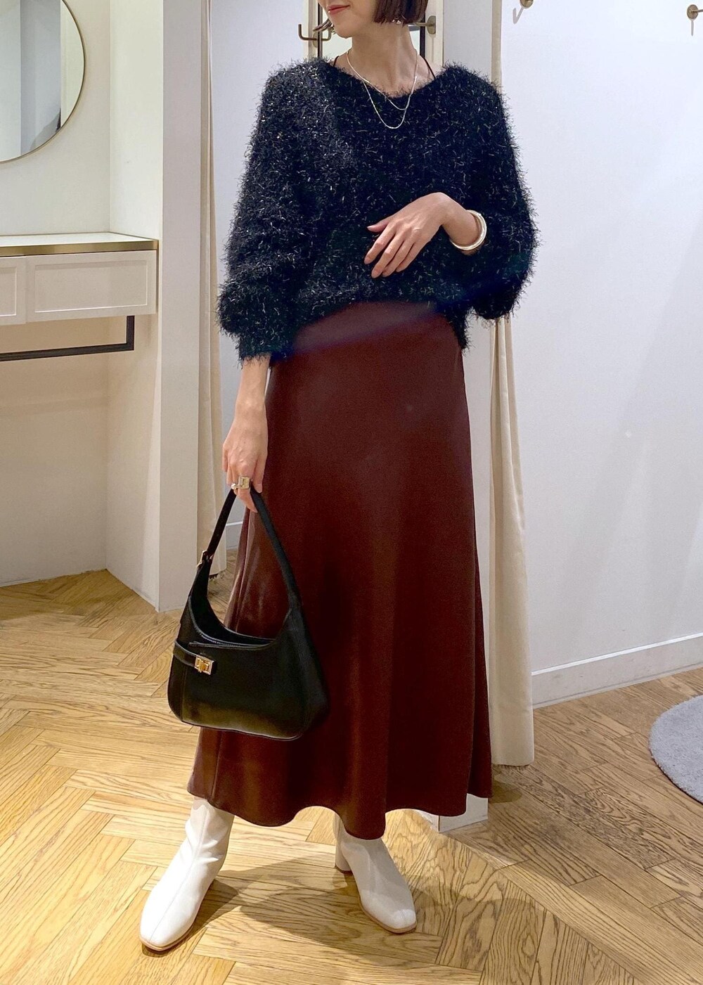 ホワイト系のブーツ、ブラック系のハンドバッグ、ブラック系のニット/セーターを着用したレディースの冬コーディネートの5枚目の写真