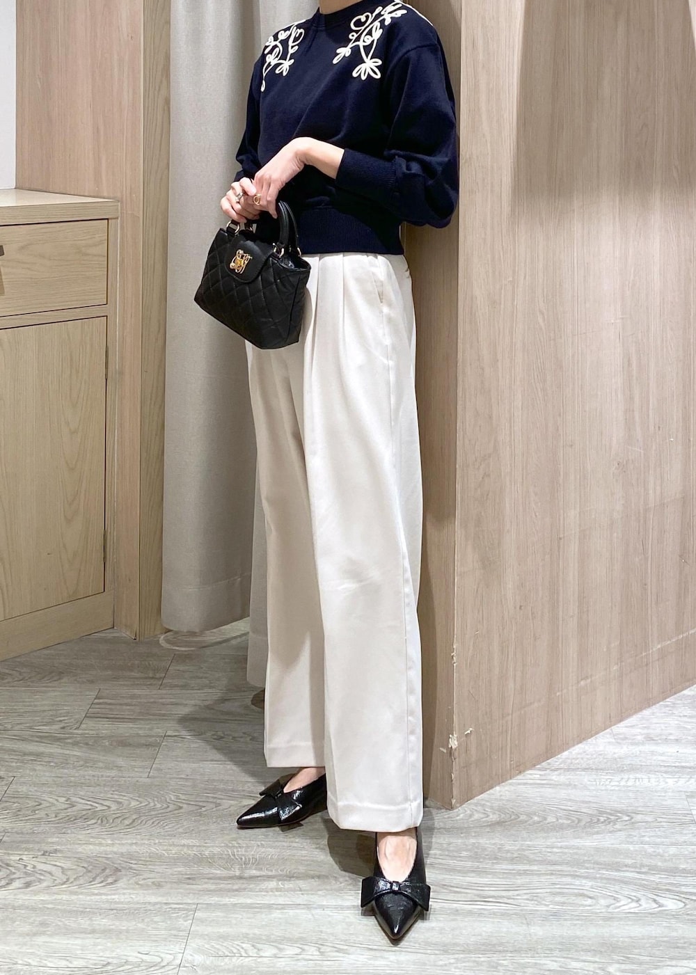 ブラック系のパンプス、ブルー系のニット/セーター、ホワイト系のスラックスを着用したレディースの冬コーディネートの6枚目の写真