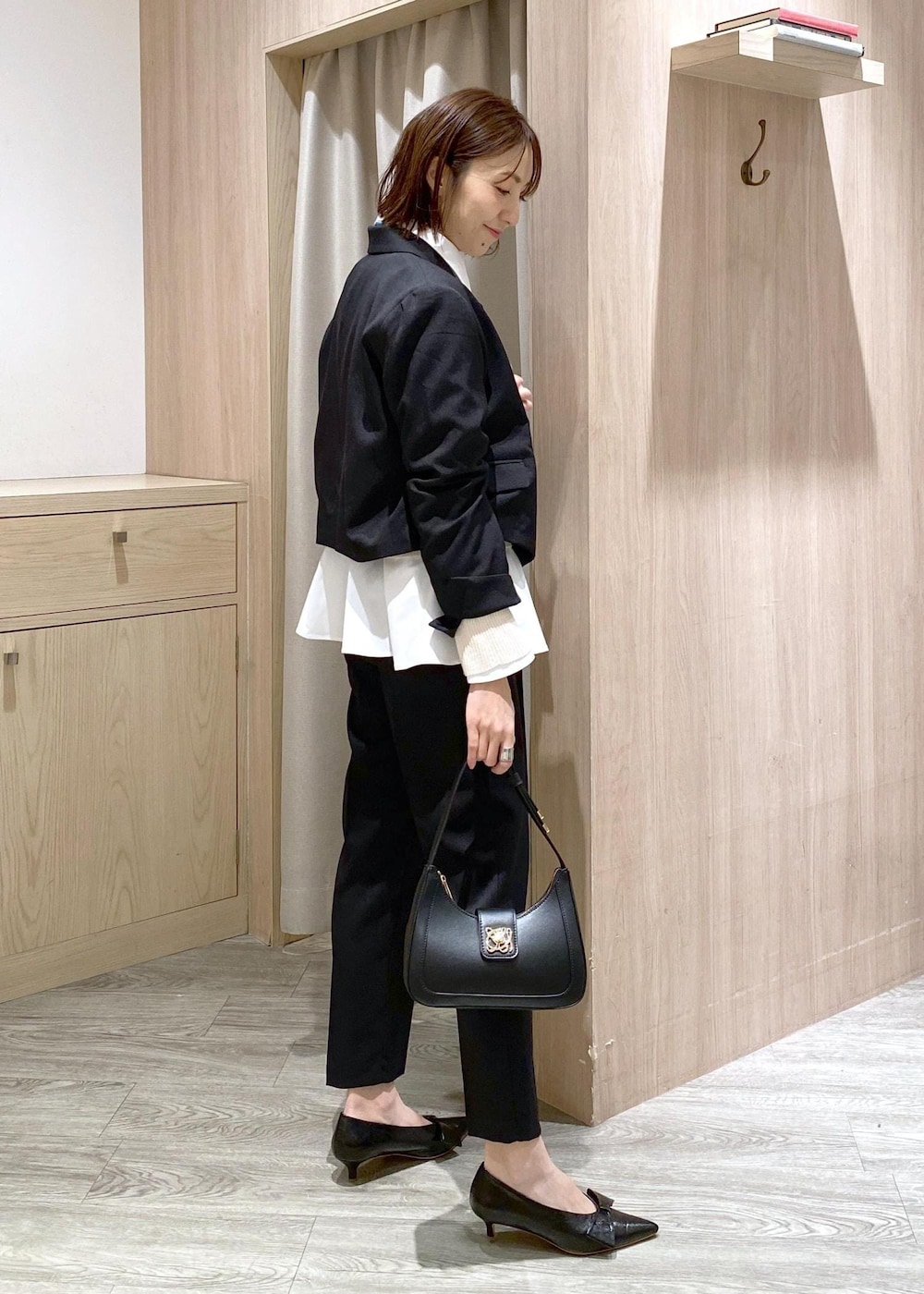 ブラック系のパンプス、ホワイト系のカーディガン/ボレロ、ブラック系のハンドバッグを着用したレディースの冬コーディネートの2枚目の写真