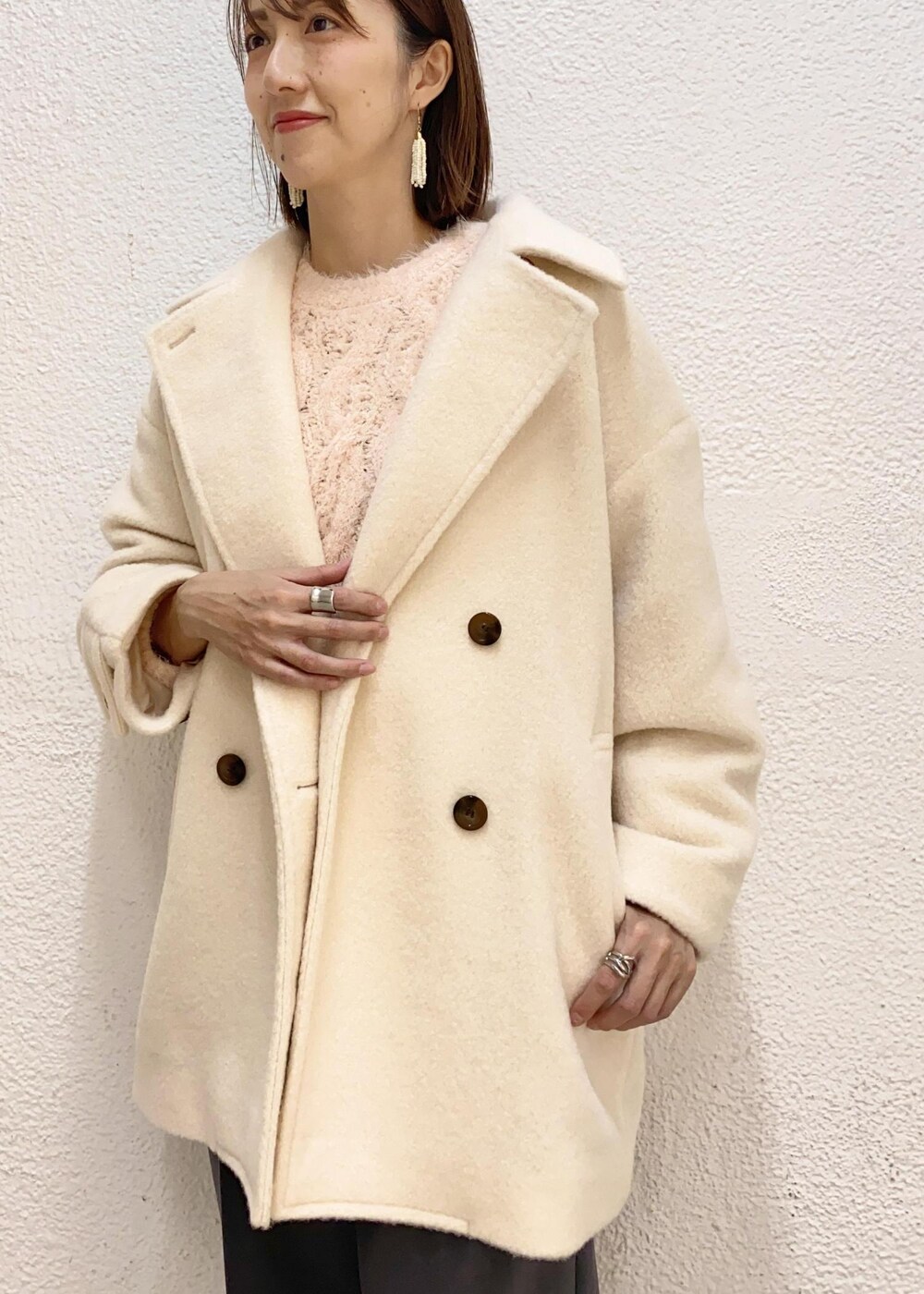 ブラック系のハンドバッグ、ホワイト系のピーコート、ピンク系のニット/セーターを着用したレディースの冬コーディネートの5枚目の写真