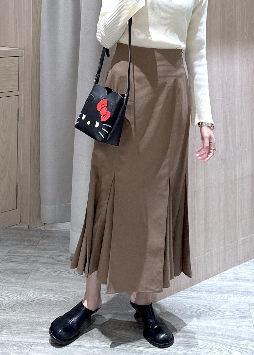 ブラウン系のスカート、ホワイト系のニット/セーター、ブラック系のショルダーバッグを着用したレディースの冬コーディネートの10枚目の写真