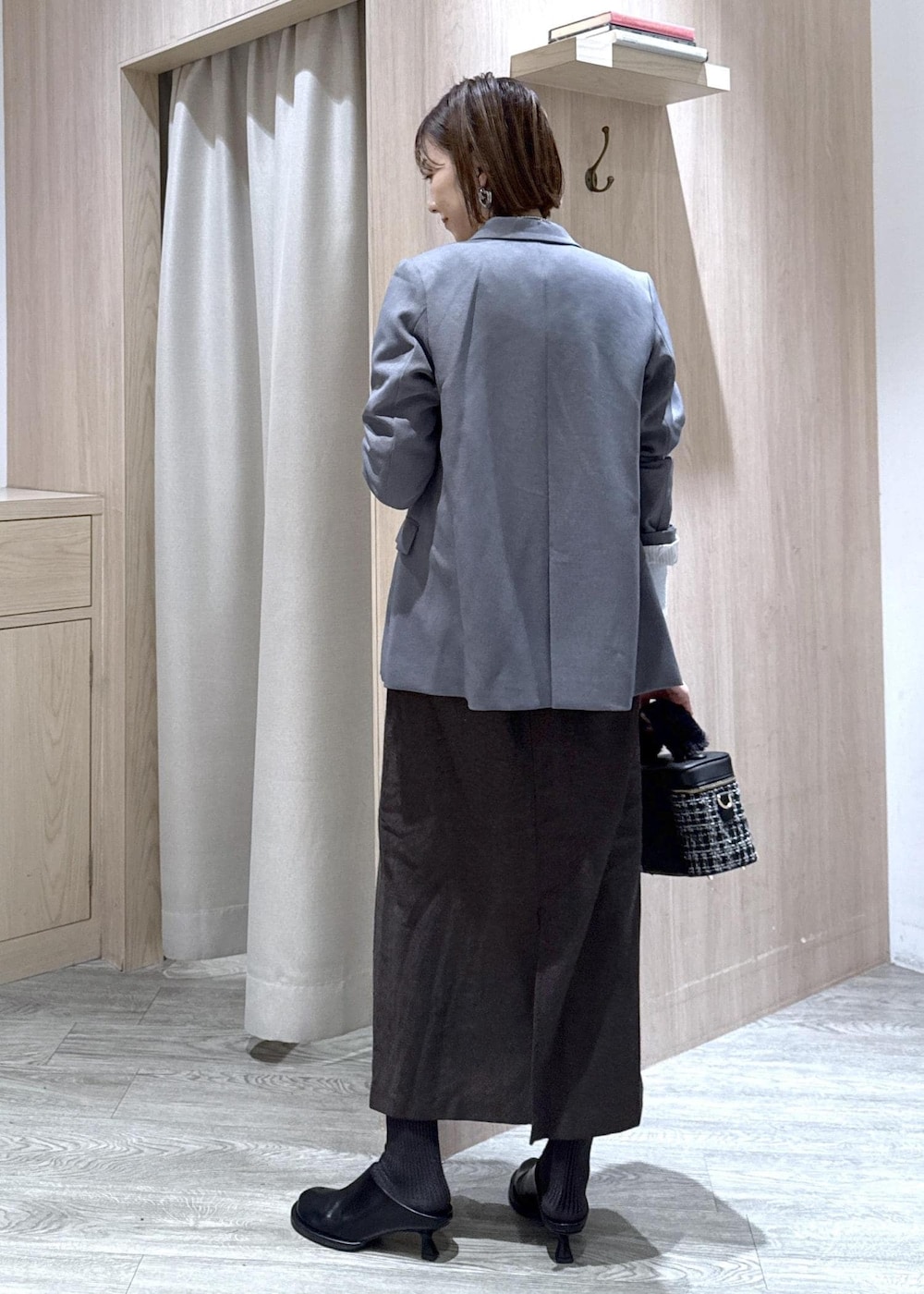 グレー系のテーラードジャケット、ブルー系のカーディガン/ボレロ、ブラウン系のスカートを着用したレディースの秋コーディネートの3枚目の写真