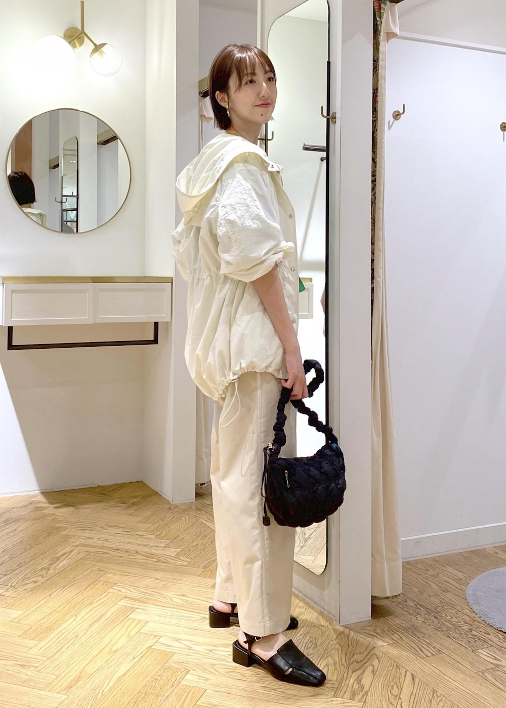 ホワイト系のスラックス、ホワイト系のマウンテンパーカー、ブラック系のサンダルを着用したレディースの春コーディネートの2枚目の写真