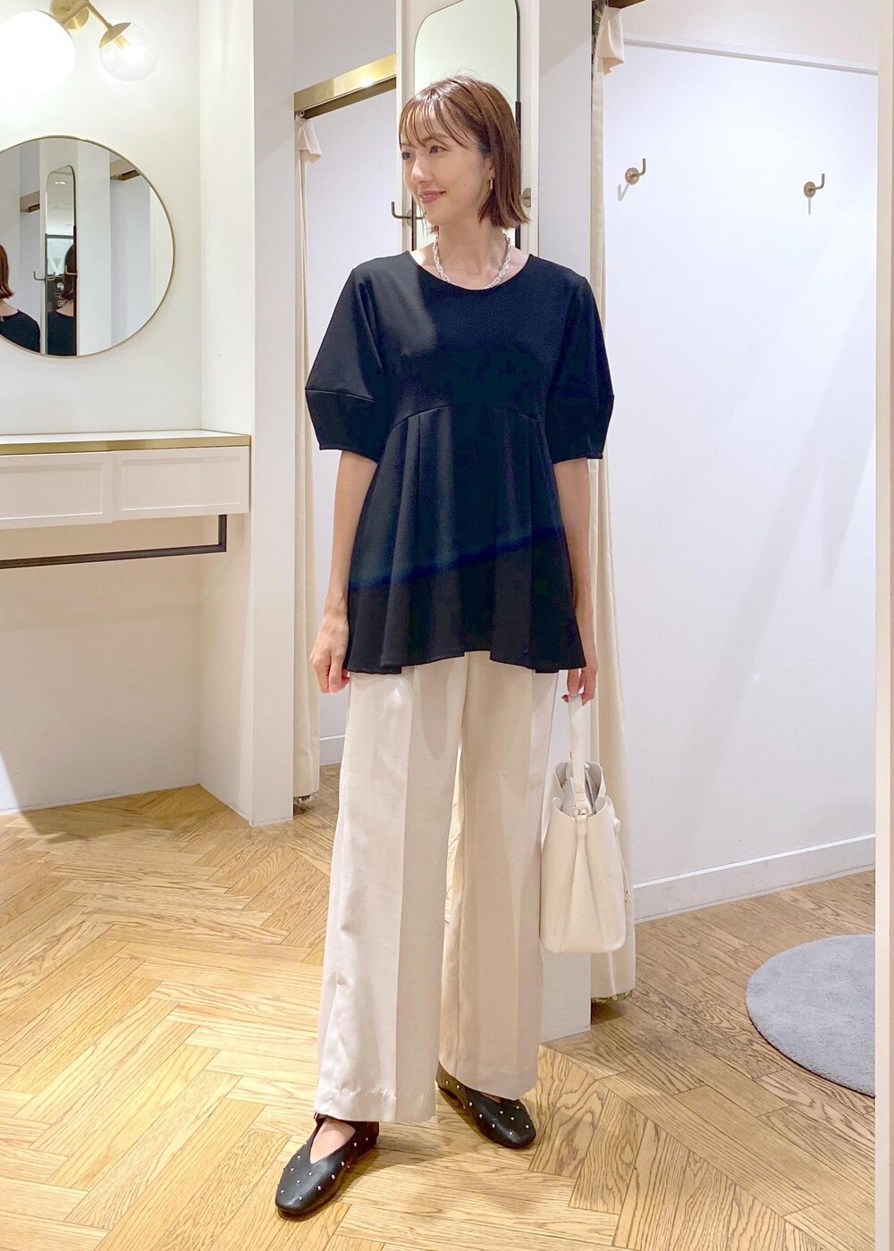 ホワイト系のショルダーバッグ、ホワイト系のスラックス、ブラック系のバレエシューズを着用したレディースの秋コーディネートの9枚目の写真