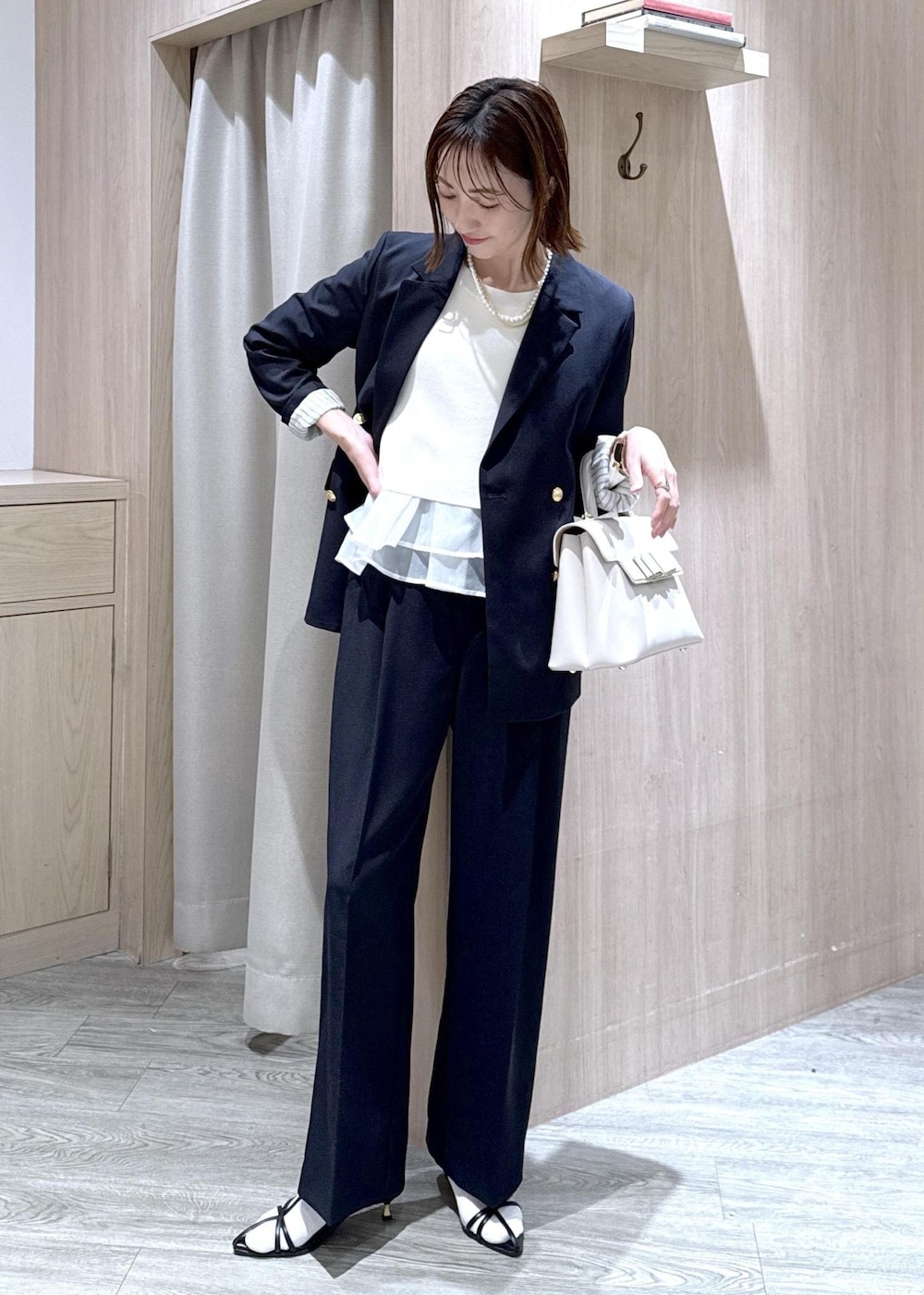 ブルー系のテーラードジャケット、ブルー系のその他パンツ、ホワイト系のハンドバッグを着用したレディースの冬コーディネートの2枚目の写真