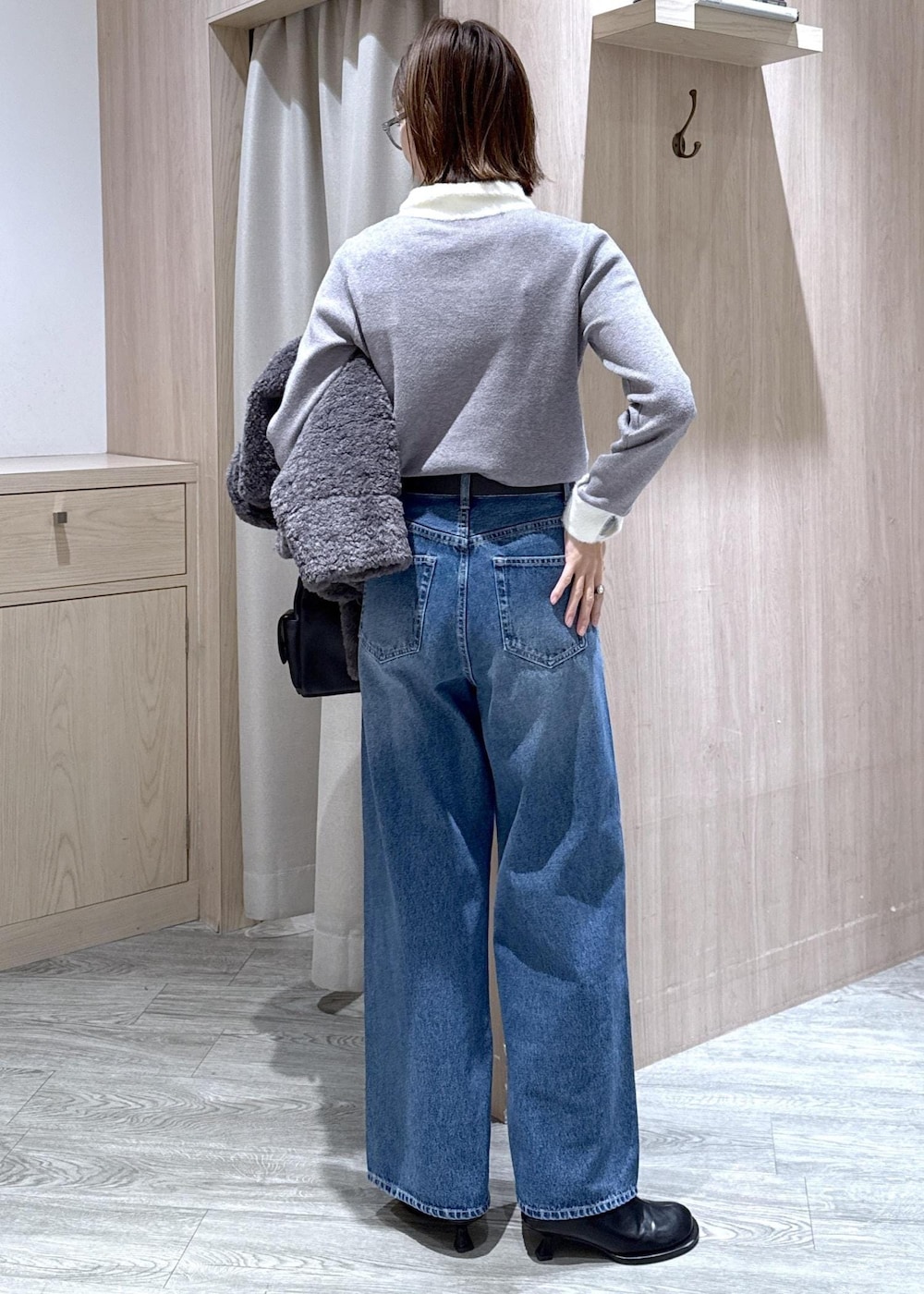 グレー系のブルゾン、グレー系のニット/セーター、ブルー系のデニムパンツを着用したレディースの冬コーディネートの6枚目の写真