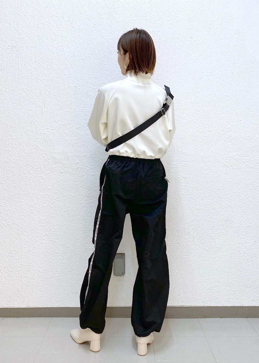 ブラウン系のボディバッグ/ウエストポーチ、ブラック系のその他パンツ、ホワイト系のその他トップスを着用したレディースの冬コーディネートの2枚目の写真