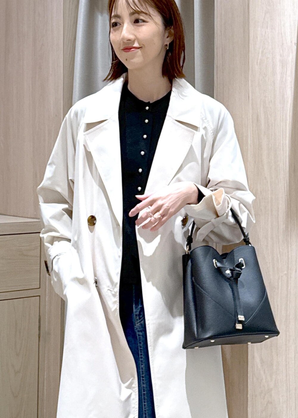 ブラック系のショルダーバッグ、ブラウン系のパンプス、ブルー系のデニムスカートを着用したレディースの春コーディネートの6枚目の写真