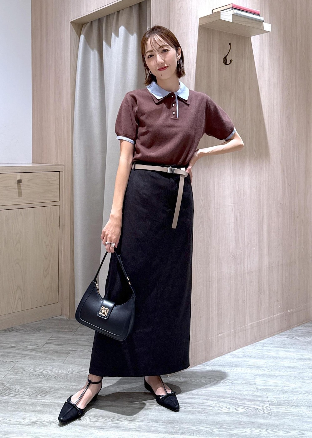 ブラック系のハンドバッグ、グレー系のスカート、ブラック系のパンプスを着用したレディースの夏コーディネートの2枚目の写真