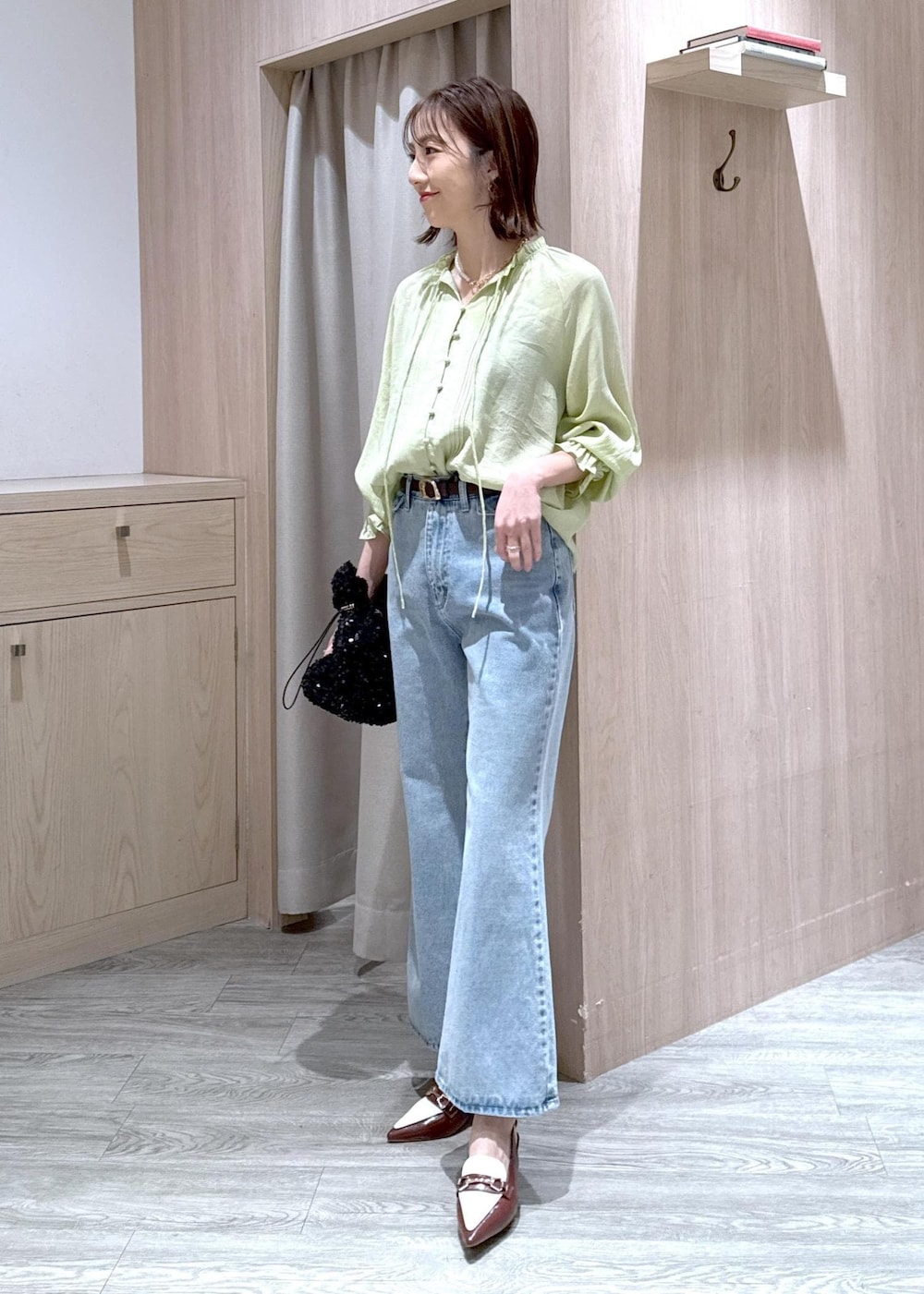 ブルー系のデニムパンツ、ブラウン系のパンプス、ブラック系のハンドバッグを着用したレディースの春コーディネートの3枚目の写真