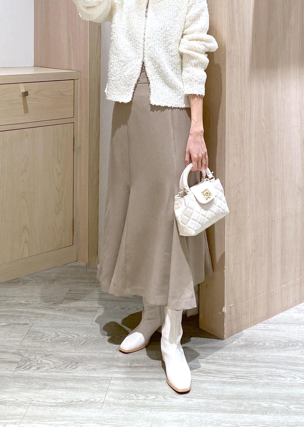 ホワイト系のブーツ、ベージュ系のスカート、ホワイト系のカーディガン/ボレロを着用したレディースの冬コーディネートの5枚目の写真