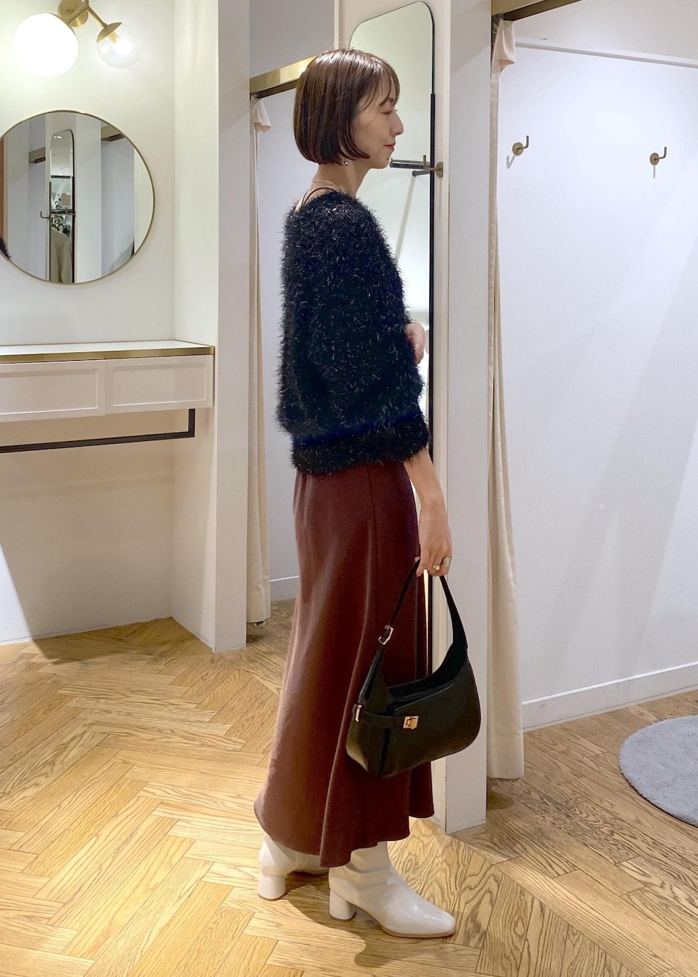 ホワイト系のブーツ、ブラック系のハンドバッグ、ブラック系のニット/セーターを着用したレディースの冬コーディネートの2枚目の写真