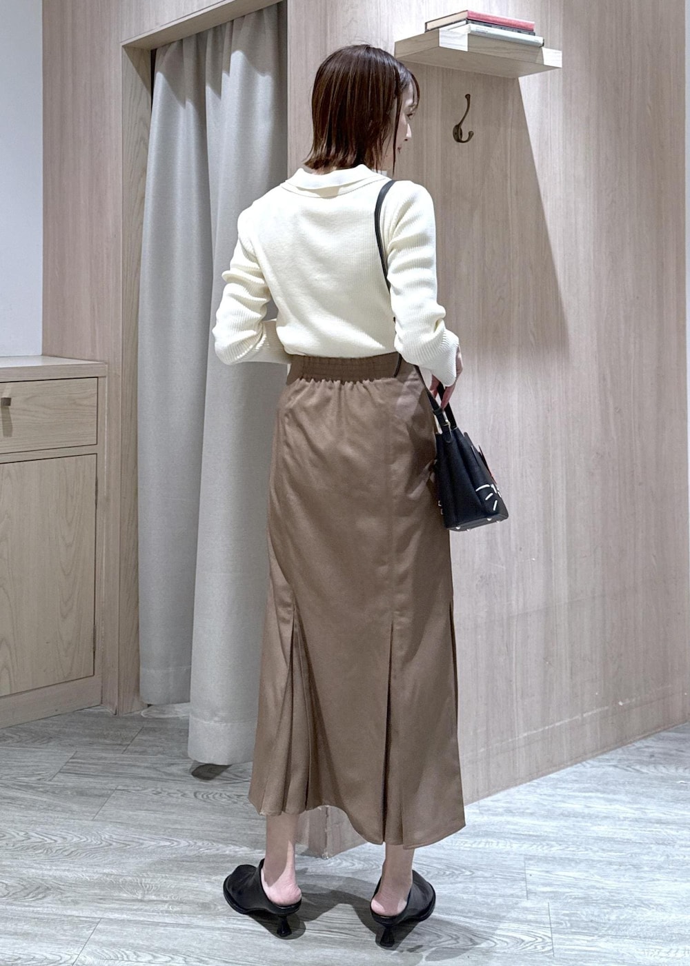 ブラウン系のスカート、ホワイト系のニット/セーター、ブラック系のショルダーバッグを着用したレディースの冬コーディネートの5枚目の写真