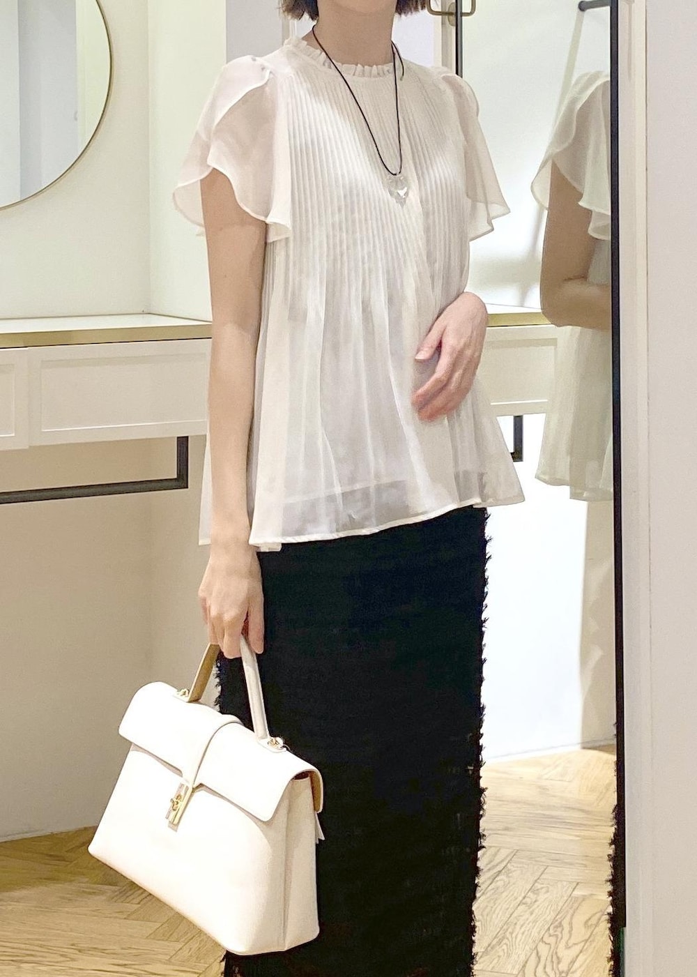 ホワイト系のハンドバッグ、ホワイト系のサンダル、ブラック系のスカートを着用したレディースの春コーディネートの3枚目の写真