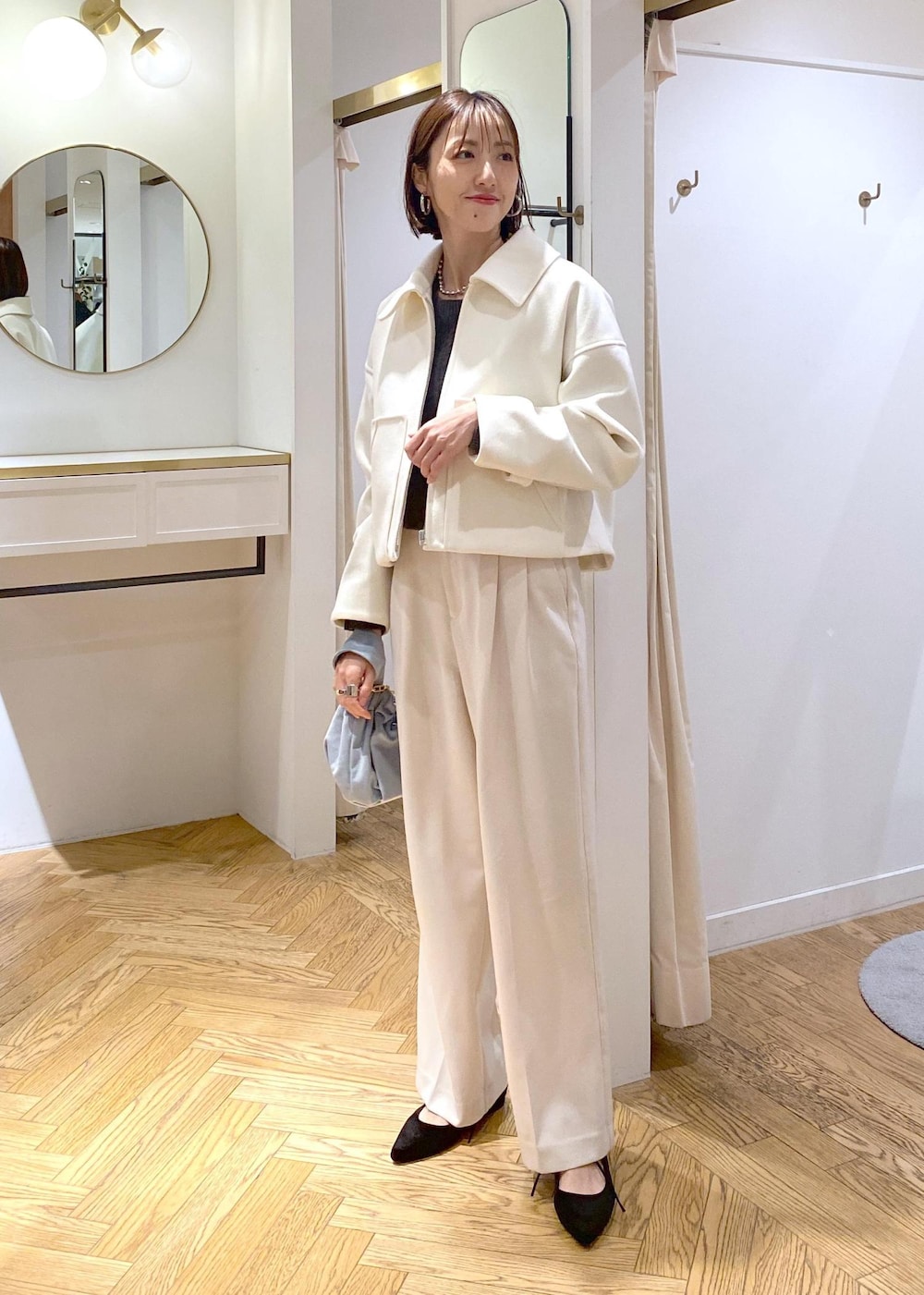 ブルー系のハンドバッグ、ホワイト系のブルゾン、ブラック系のパンプスを着用したレディースの冬コーディネートの3枚目の写真