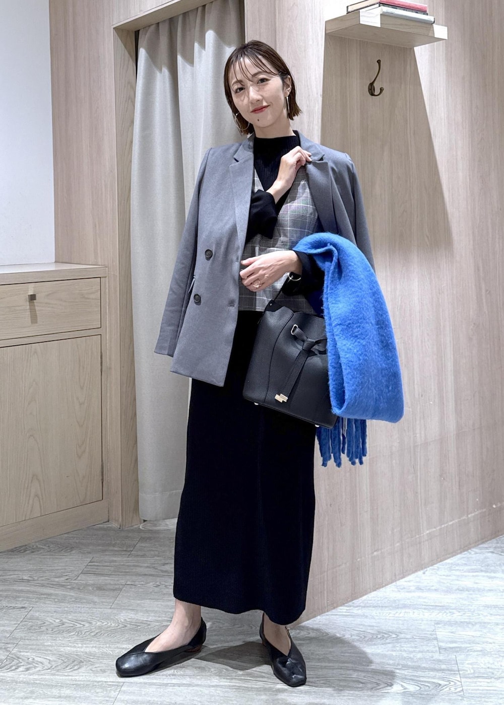 グレー系のテーラードジャケット、ブラック系のショルダーバッグ、ブラック系のワンピースを着用したレディースの冬コーディネートの10枚目の写真