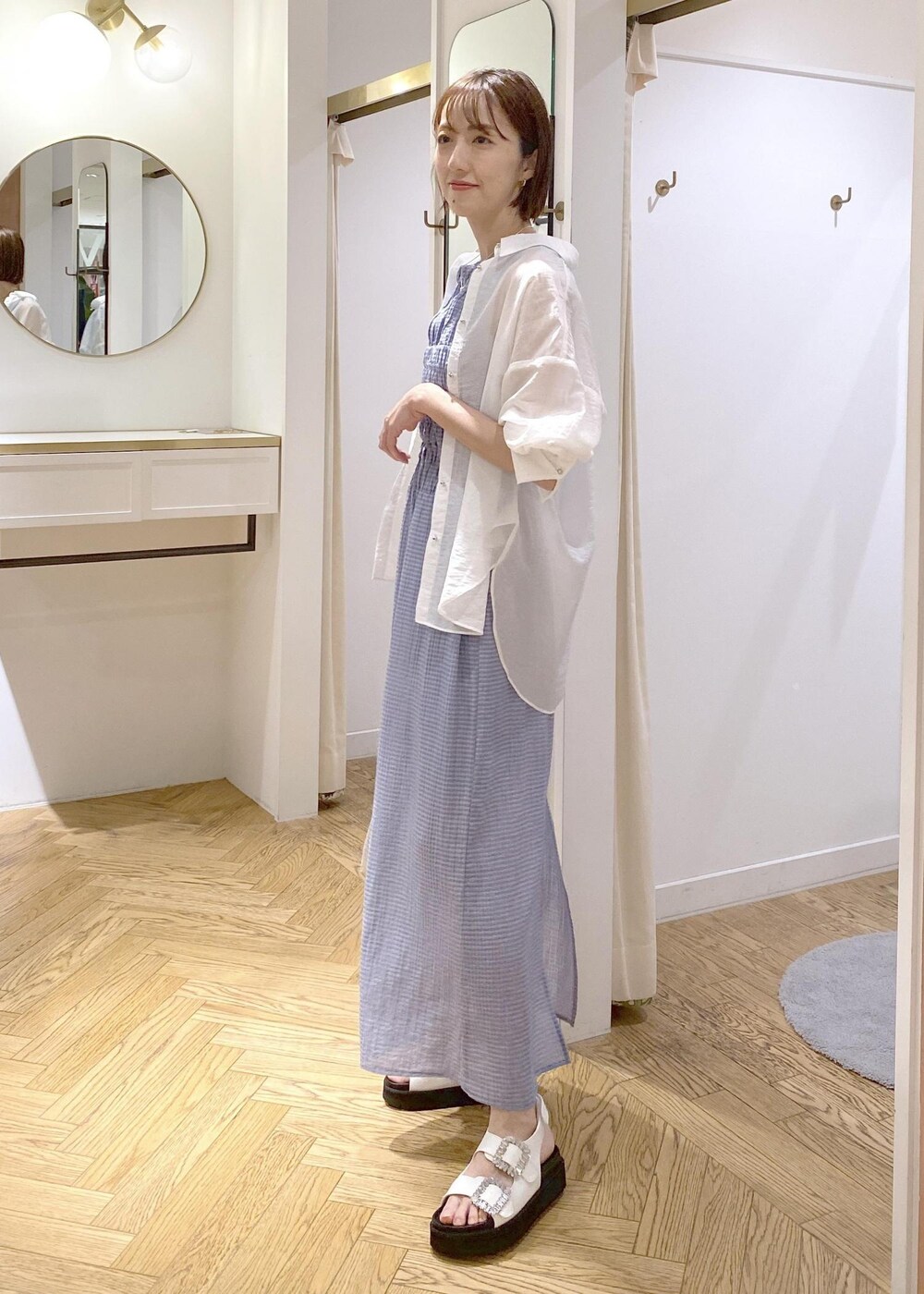 ホワイト系のサンダル、ブルー系のワンピース、シルバー系のショルダーバッグを着用したレディースの夏コーディネートの2枚目の写真