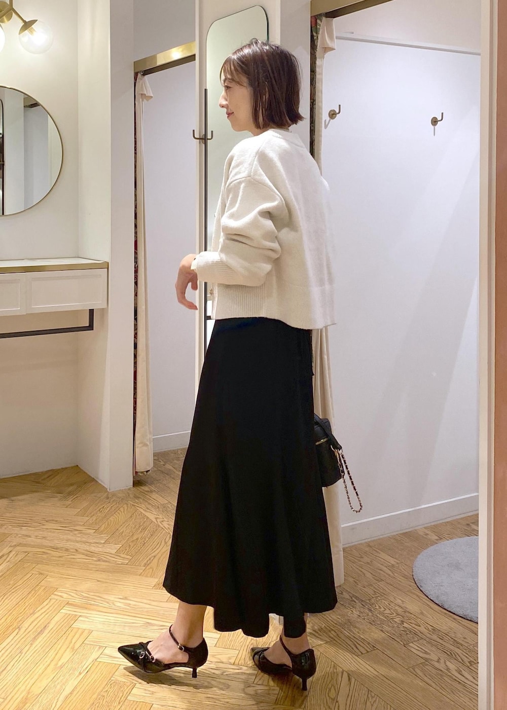 ホワイト系のカーディガン/ボレロ、ブラック系のスカート、ブラック系のパンプスを着用したレディースの冬コーディネートの2枚目の写真